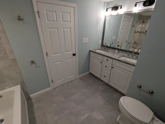 a bathroom with a granite countertop toilet sink and mirror