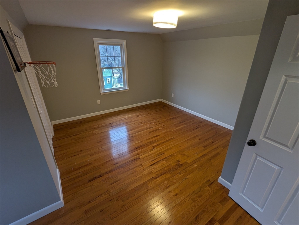185 Mystic Street, Unit 2 Arlington, MA 02474 - Photo 19 of 33 an empty room with wooden floor and windows