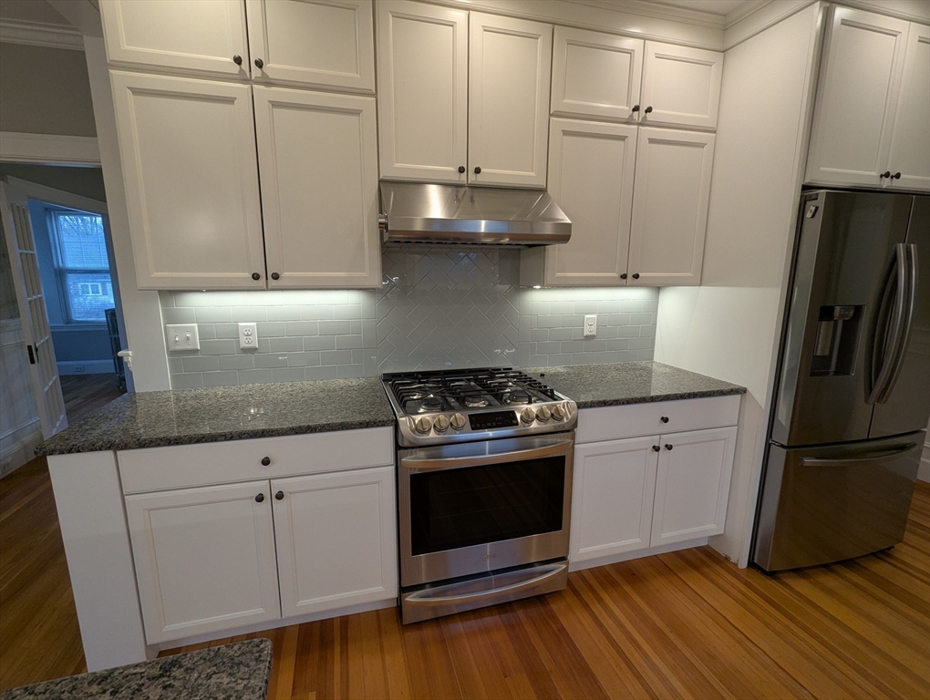 185 Mystic Street, Unit 2 Arlington, MA 02474 - Photo 2 of 33 a kitchen with granite countertop a wooden floor and a stove top oven