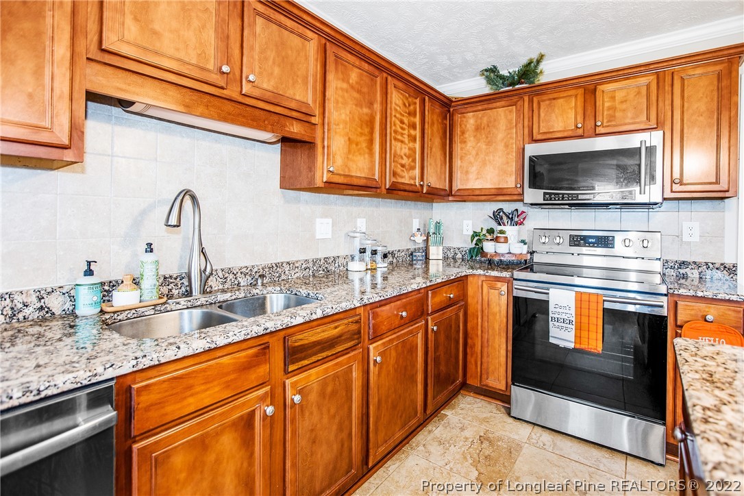 1909 Yellowbrick Road Fayetteville, NC 28314 - Photo 16 of 25 a kitchen with stainless steel appliances granite countertop a sink stove and microwave