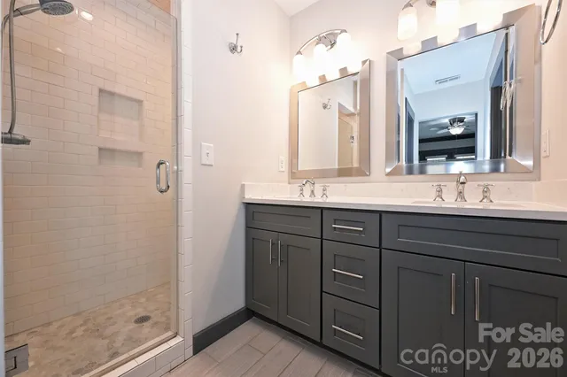 a bathroom with a double vanity sink mirror and shower