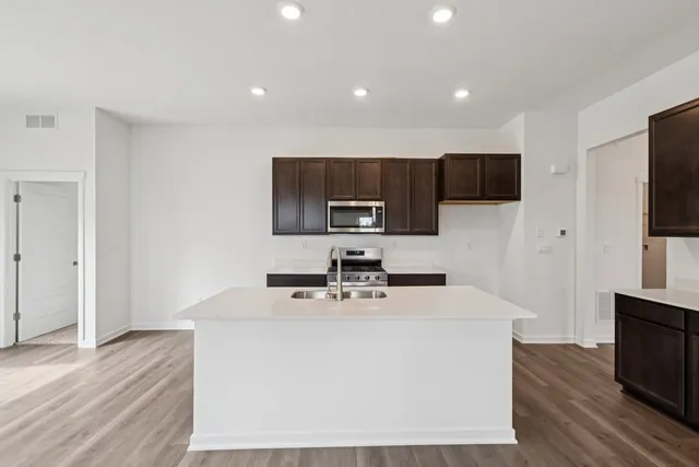 a kitchen with kitchen island a sink a stove a microwave and wooden floor