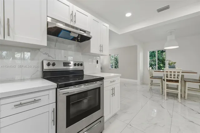 a kitchen with stainless steel appliances granite countertop a stove a sink and a microwave