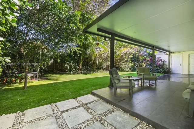 a view of a patio with a table chairs and a small yard