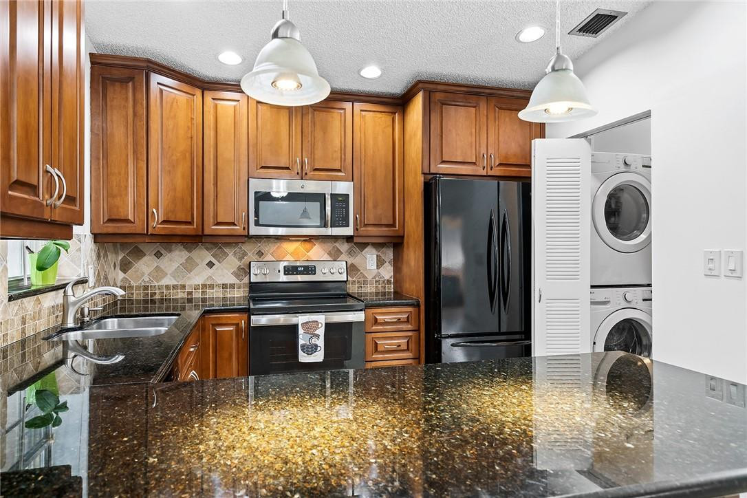 Undisclosed Address Boca Raton, FL 33428 - Photo 12 of 35 a kitchen with kitchen island granite countertop a stove a sink dishwasher a refrigerator and a microwave oven with granite countertops