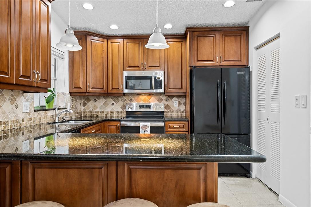 Undisclosed Address Boca Raton, FL 33428 - Photo 14 of 35 a kitchen with kitchen island granite countertop a sink window and cabinets
