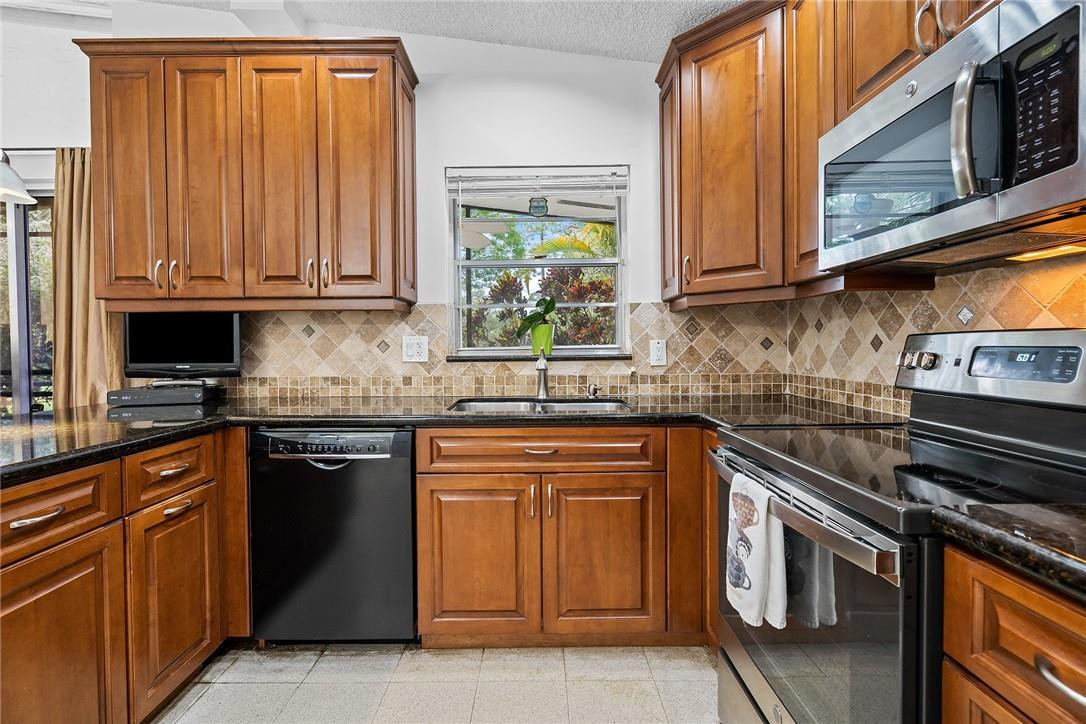 Undisclosed Address Boca Raton, FL 33428 - Photo 16 of 35 a kitchen with stainless steel appliances granite countertop a stove a sink and a microwave