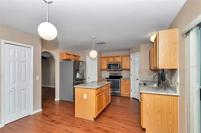 a kitchen with stainless steel appliances granite countertop a sink refrigerator and cabinets
