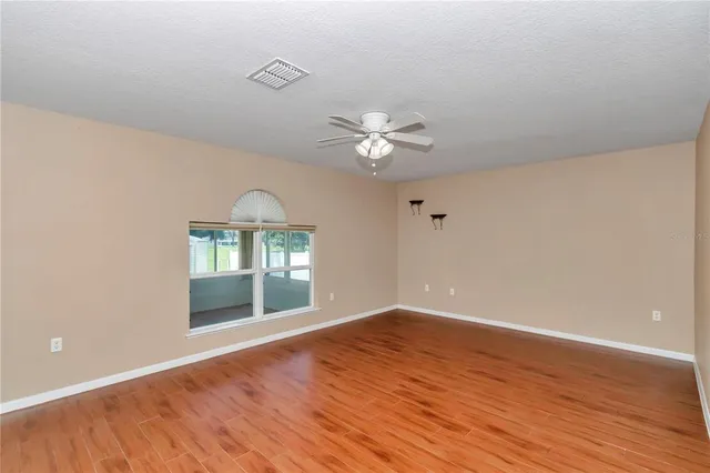 a view of an empty room with window and wooden floor