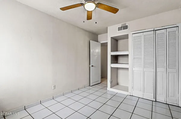 an empty room with windows and fan