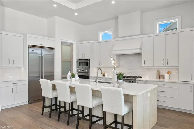 a kitchen with stainless steel appliances a dining table chairs and white cabinets