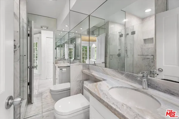 a bathroom with a granite countertop sink toilet a large mirror a shower and a bathtub
