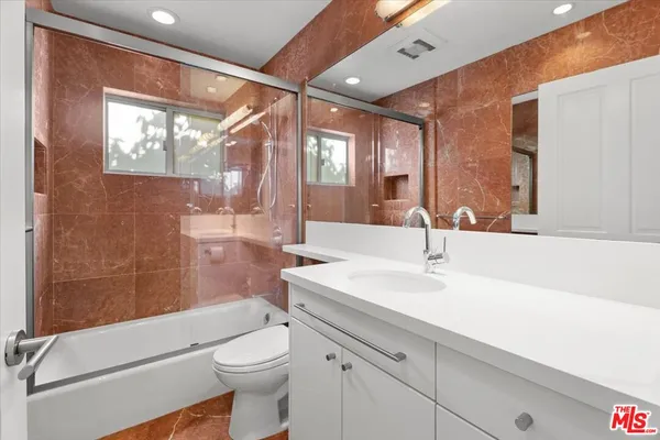 a bathroom with a sink a toilet a mirror and shower