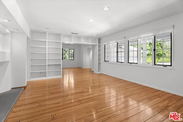 a view of empty room with wooden floor and window