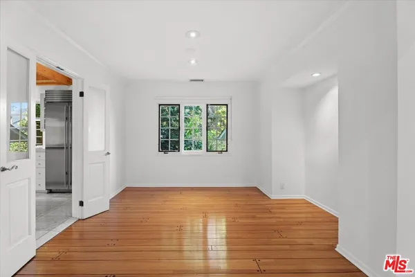 a view of empty room with wooden floor and fan