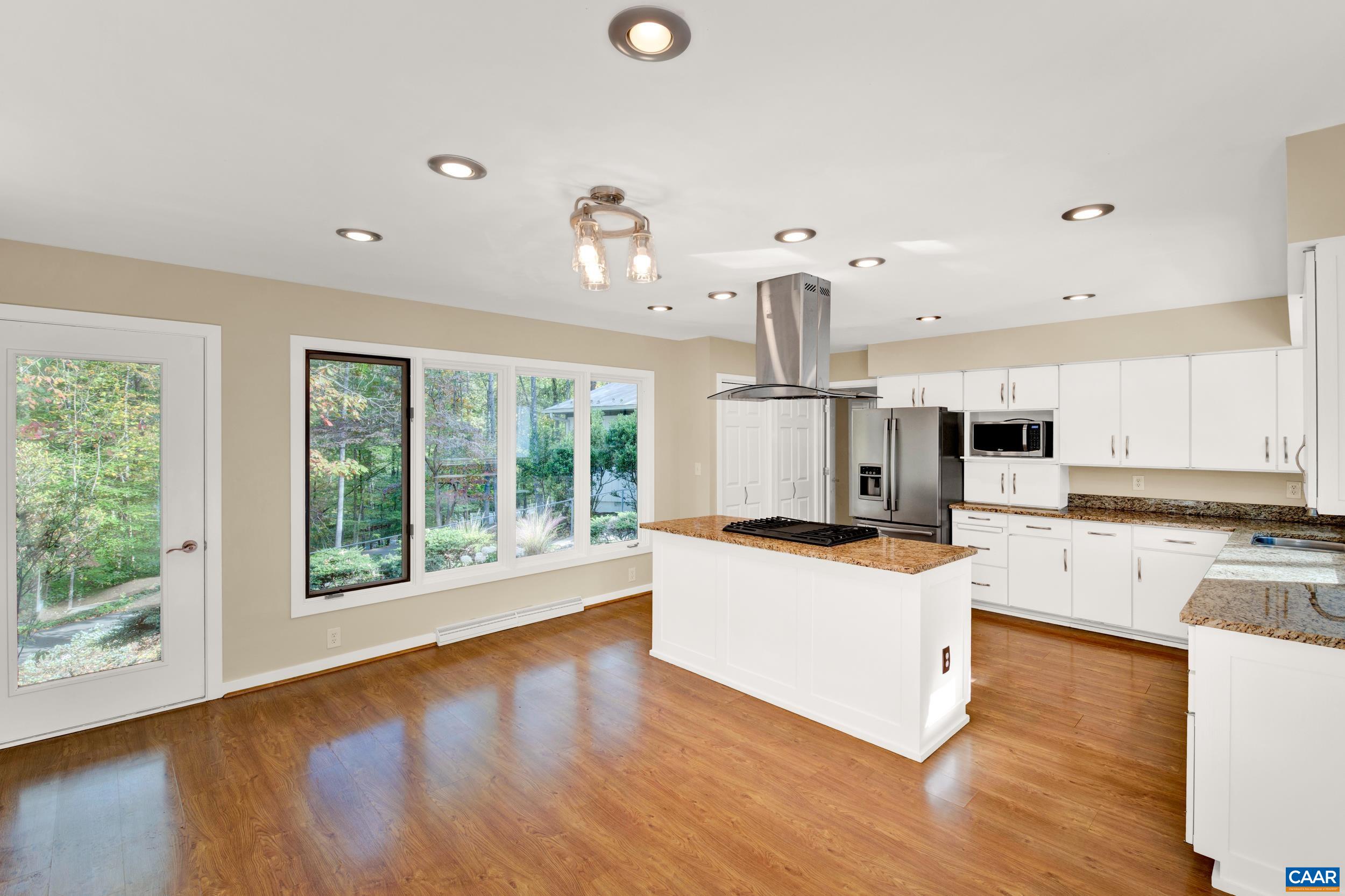 1065 Tilman Road Charlottesville, VA 22901 - Photo 37 of 70 a kitchen with stainless steel appliances kitchen island wooden floors and white cabinets