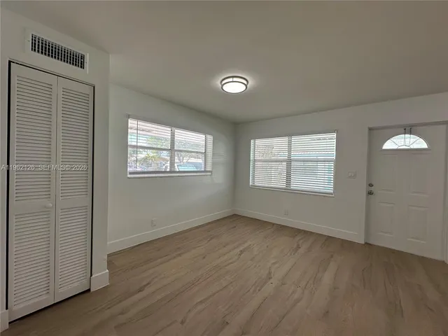 a view of an empty room with wooden floor and a window