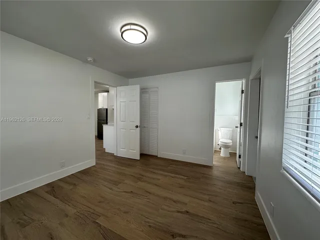 a view of empty room with wooden floor and window