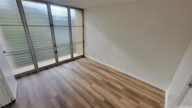 a view of an empty room with wooden floor and a window