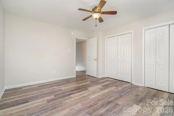 an empty room with wooden floor fan and windows