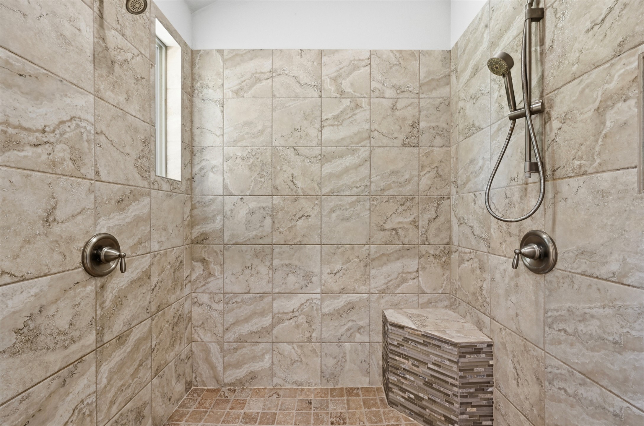 387 Corral Road Smithville, TX 78957 - Photo 20 of 40 Tiled shower enclosure featuring a built-in bench, dual shower controls, a handheld shower fixture, and a frosted window