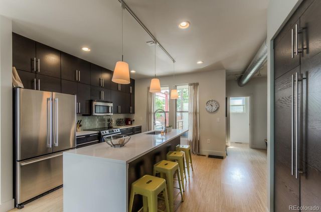 a kitchen with stainless steel appliances a refrigerator and a view of living room