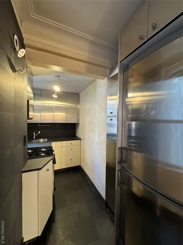 a kitchen with a refrigerator and white cabinets