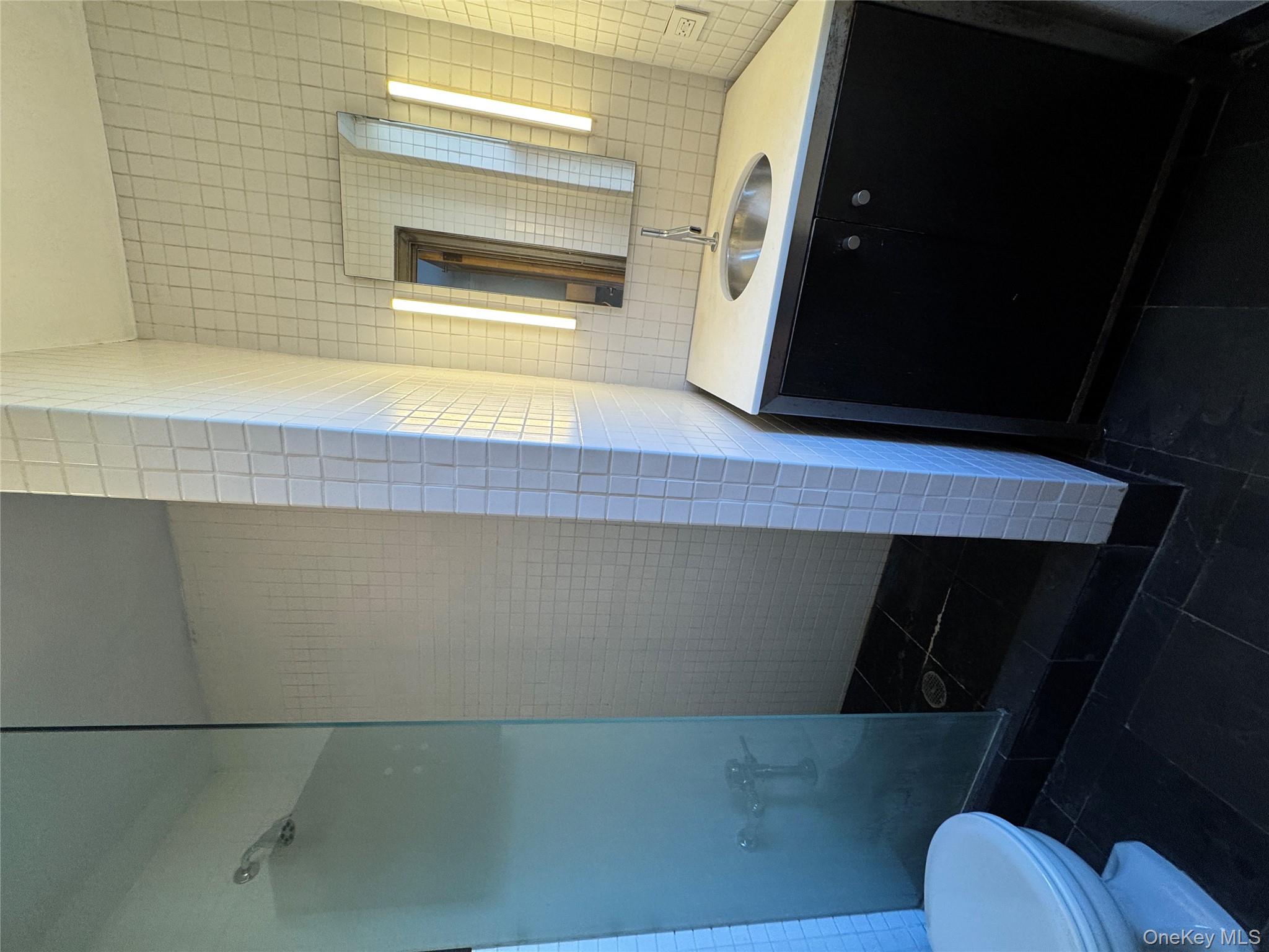 333 East 53rd Street, Unit 5C Manhattan, NY 10022 - Photo 15 of 27 a bathroom with a sink and mirror with toilet