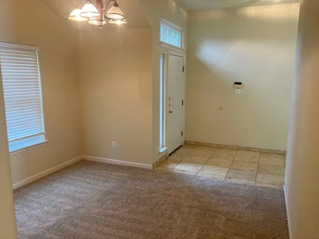 en empty room with windows and chandelier fan