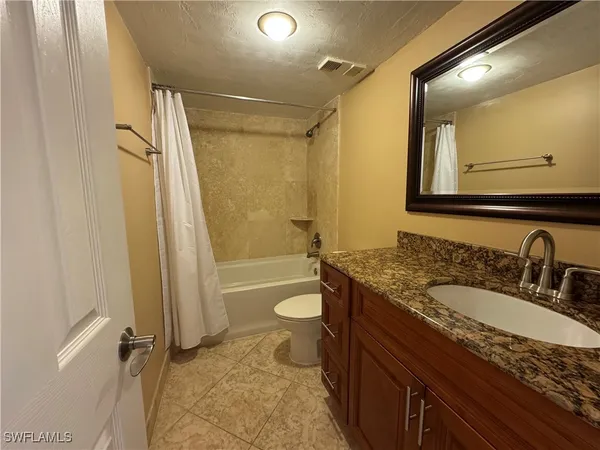 a bathroom with a granite countertop sink toilet and shower