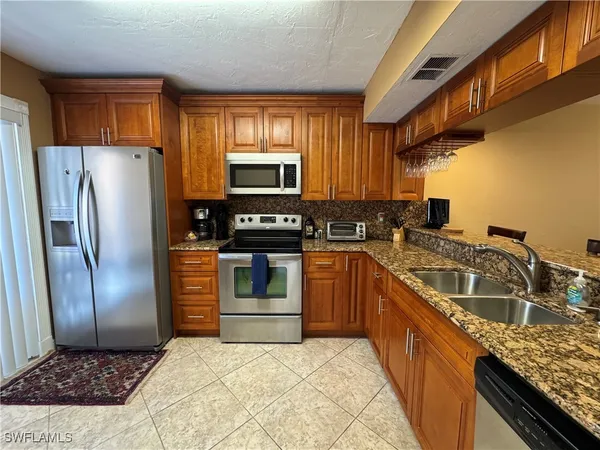 a kitchen with stainless steel appliances granite countertop a refrigerator a stove a sink and dishwasher