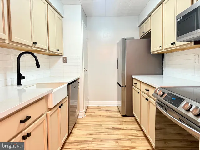 a kitchen with stainless steel appliances a stove refrigerator and cabinets