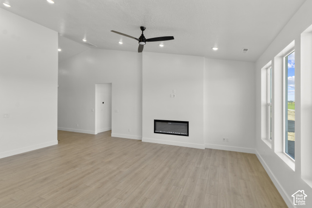 205 East 690th Street North Logan, UT 84321 - Photo 39 of 52 Spacious living area featuring wood-finish flooring, a contemporary electric fireplace, and a ceiling fan