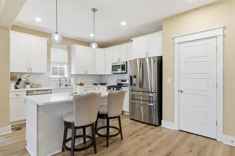 a kitchen with kitchen island white cabinets and stainless steel appliances