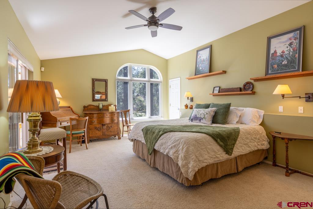 171 Deer Trail Road Durango, CO 81303 - Photo 15 of 35 a spacious bedroom with a bed a table chair and a chandelier