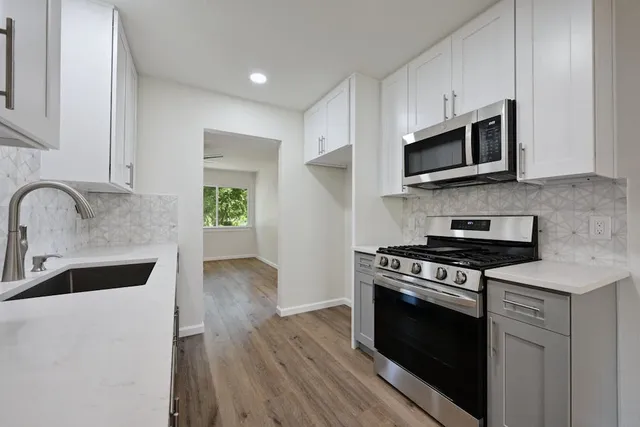 a kitchen with stainless steel appliances granite countertop a stove a sink and a microwave