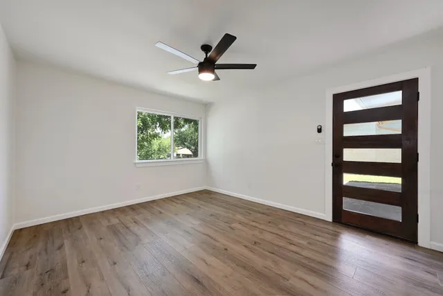 an empty room with wooden floor closet fan and windows