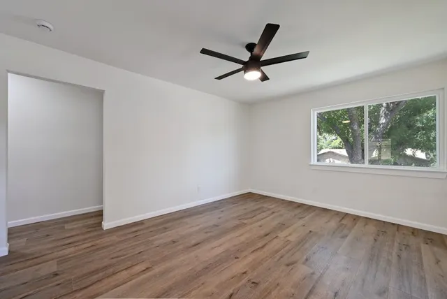 a view of a big room with wooden floor and windows