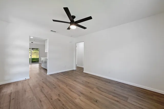 a view of empty room with wooden floor and ceiling fan
