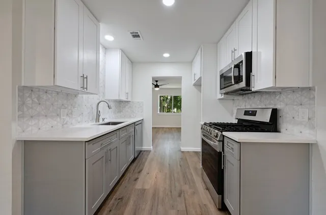 a kitchen with stainless steel appliances granite countertop a sink stove and cabinets