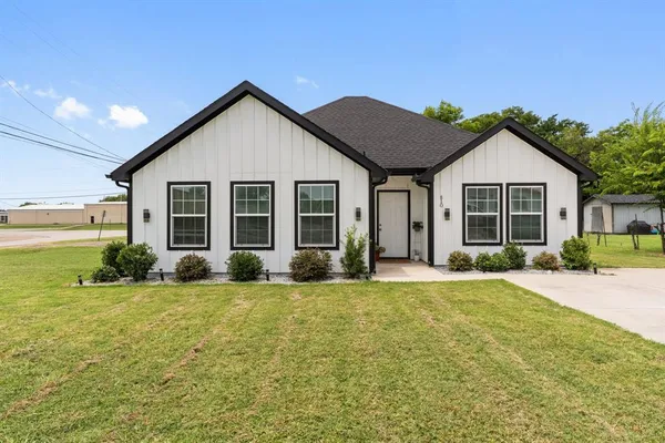 a view of a house with a yard and large tree