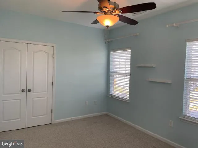 an empty room with windows and a chandelier fan