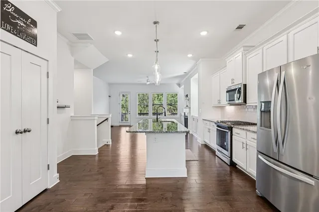 a large kitchen with stainless steel appliances granite countertop a refrigerator a oven a stove and a wooden floors