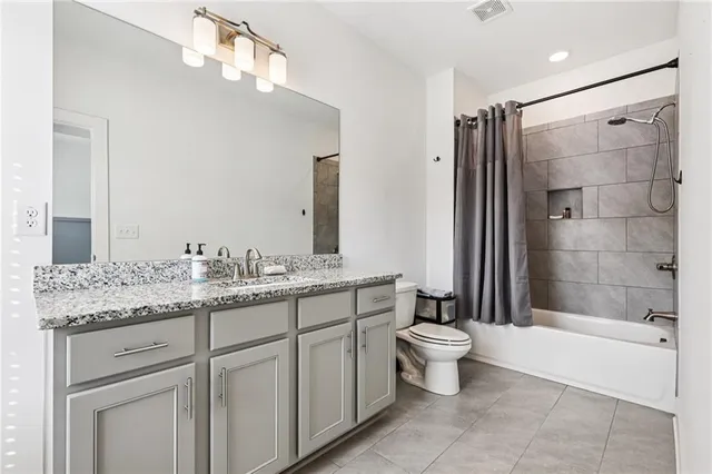 a bathroom with a granite countertop sink a toilet a mirror and shower