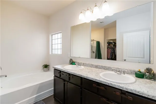 a bathroom with a granite countertop sink a bathtub a mirror and vanity
