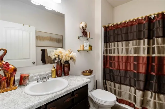 a bathroom with a sink a toilet a shower curtain and a mirror