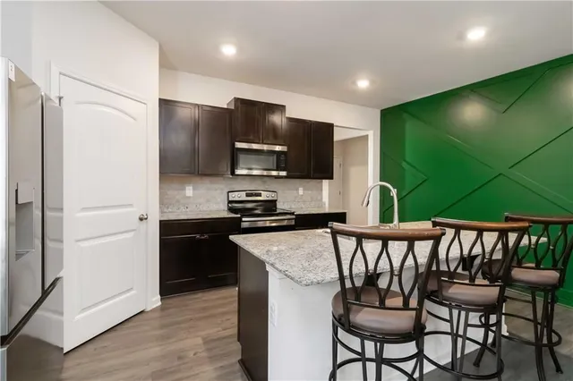 a kitchen with stainless steel appliances granite countertop a refrigerator a stove a sink and a microwave