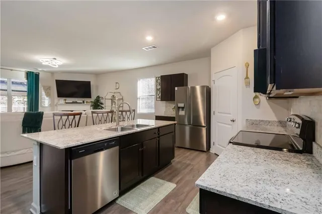 a kitchen with stainless steel appliances kitchen island granite countertop a sink stove and refrigerator