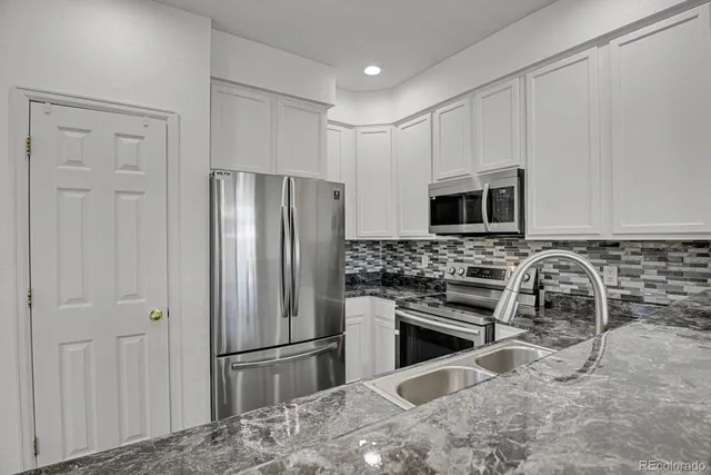 a kitchen with stainless steel appliances granite countertop a refrigerator and a stove top oven