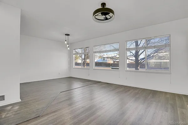 a view of an empty room with window and wooden floor
